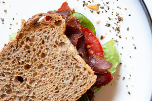 a biltong, lettuce and tomato sandwich on wheat bread closeup